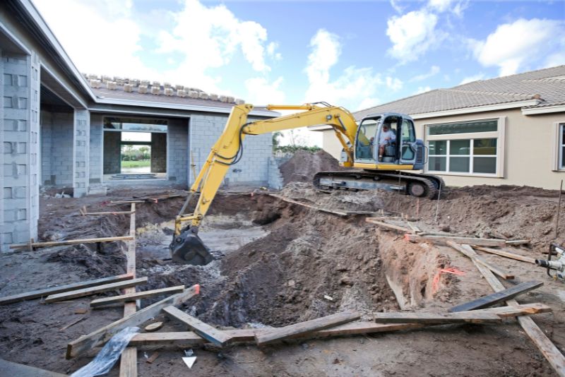 yellow excavator digging out pool area